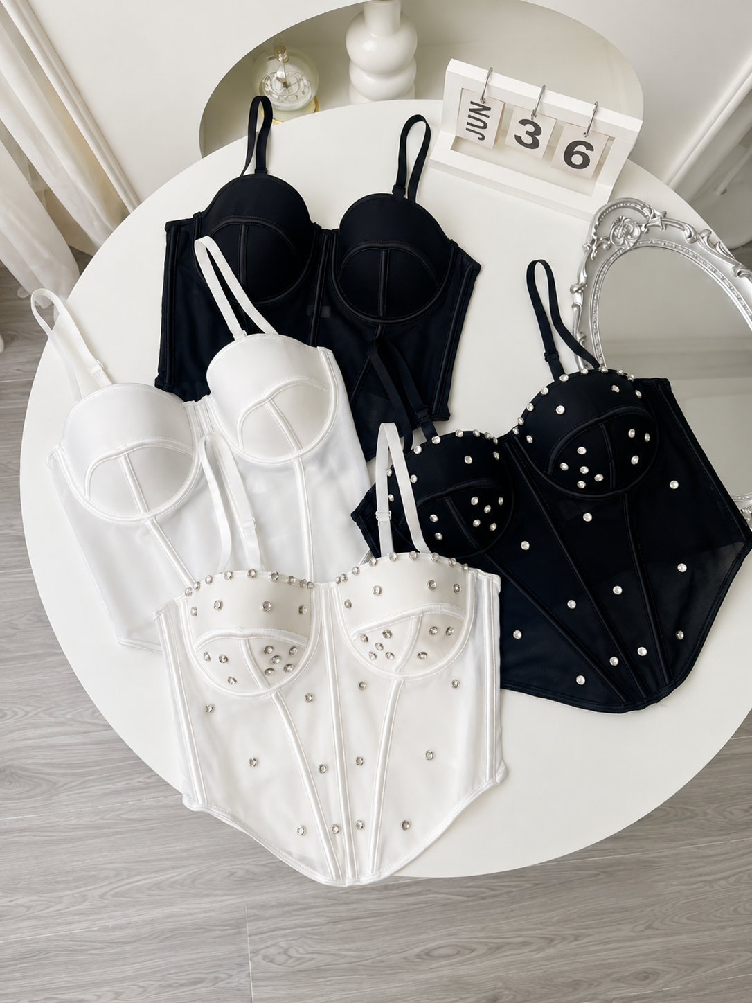 Black and white lingerie set on a round white table with a calendar in the background.