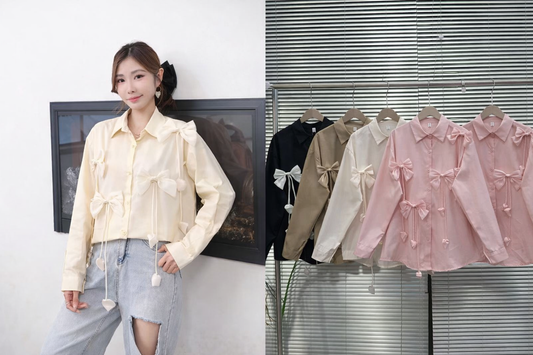 Woman wearing a light-colored blouse with bow details, standing next to a display of similar shirts.
